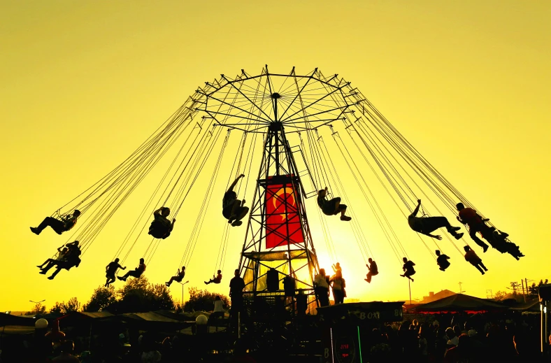 carnival ride with people riding on it at sunset