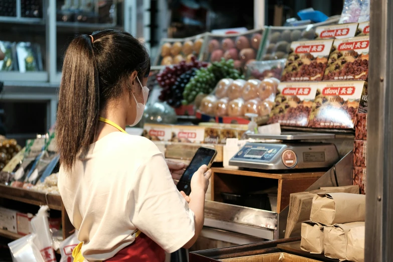 a woman stands at the food section of a store holding a tablet