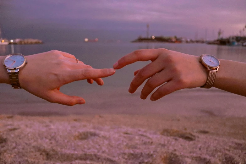 two people holding hands over each other at the beach
