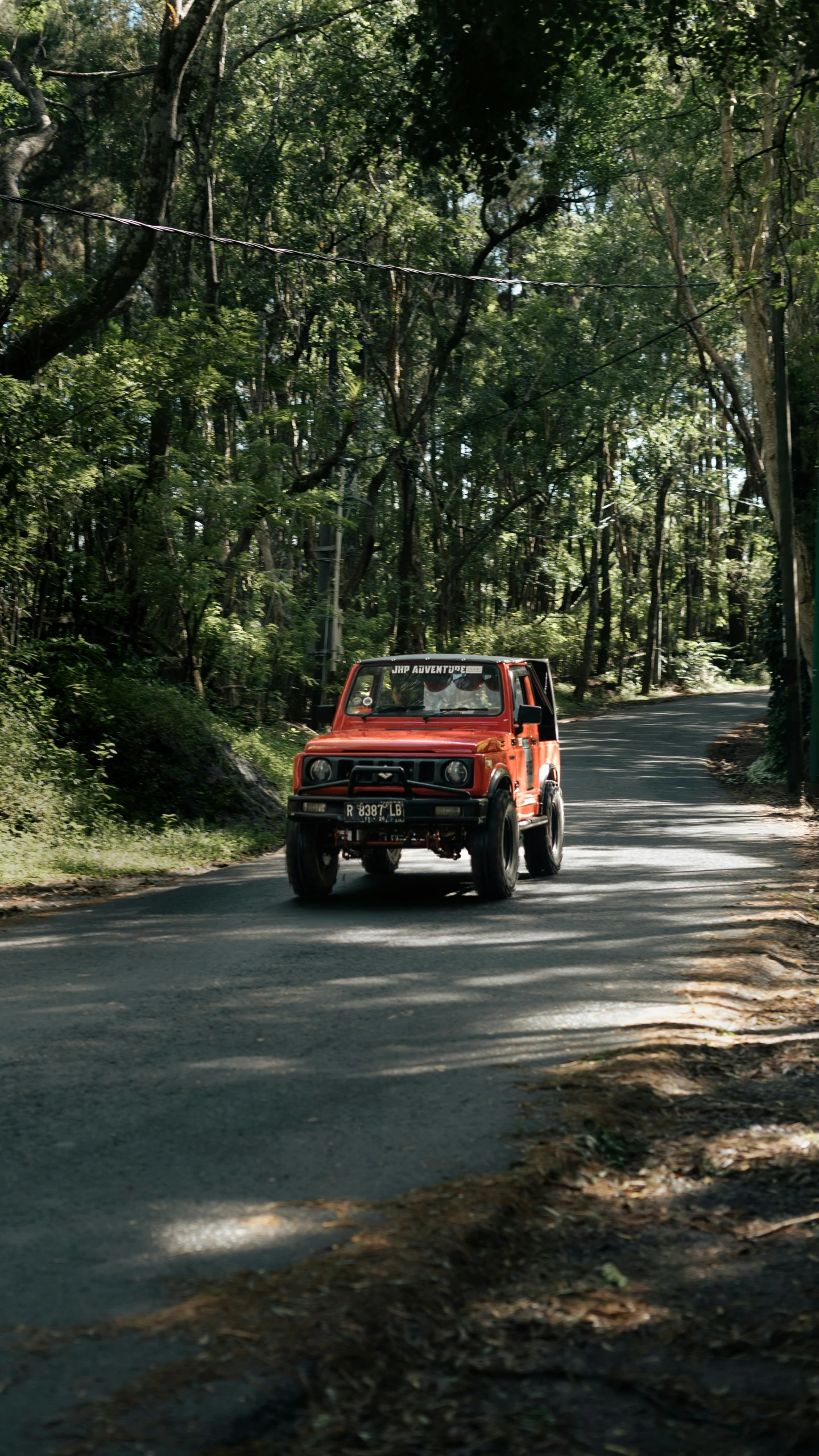 red truck driving down the road near trees