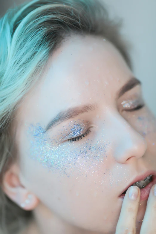 a woman's face painted with glitter and silver powder