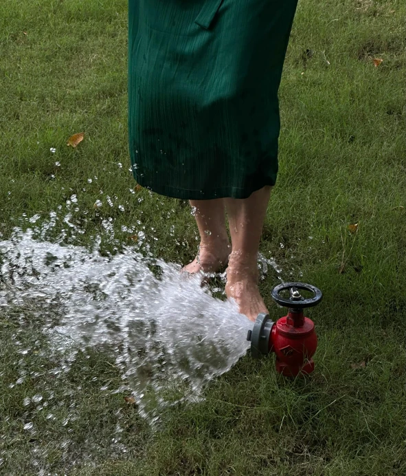 woman in green dress holding a hose and sprays water