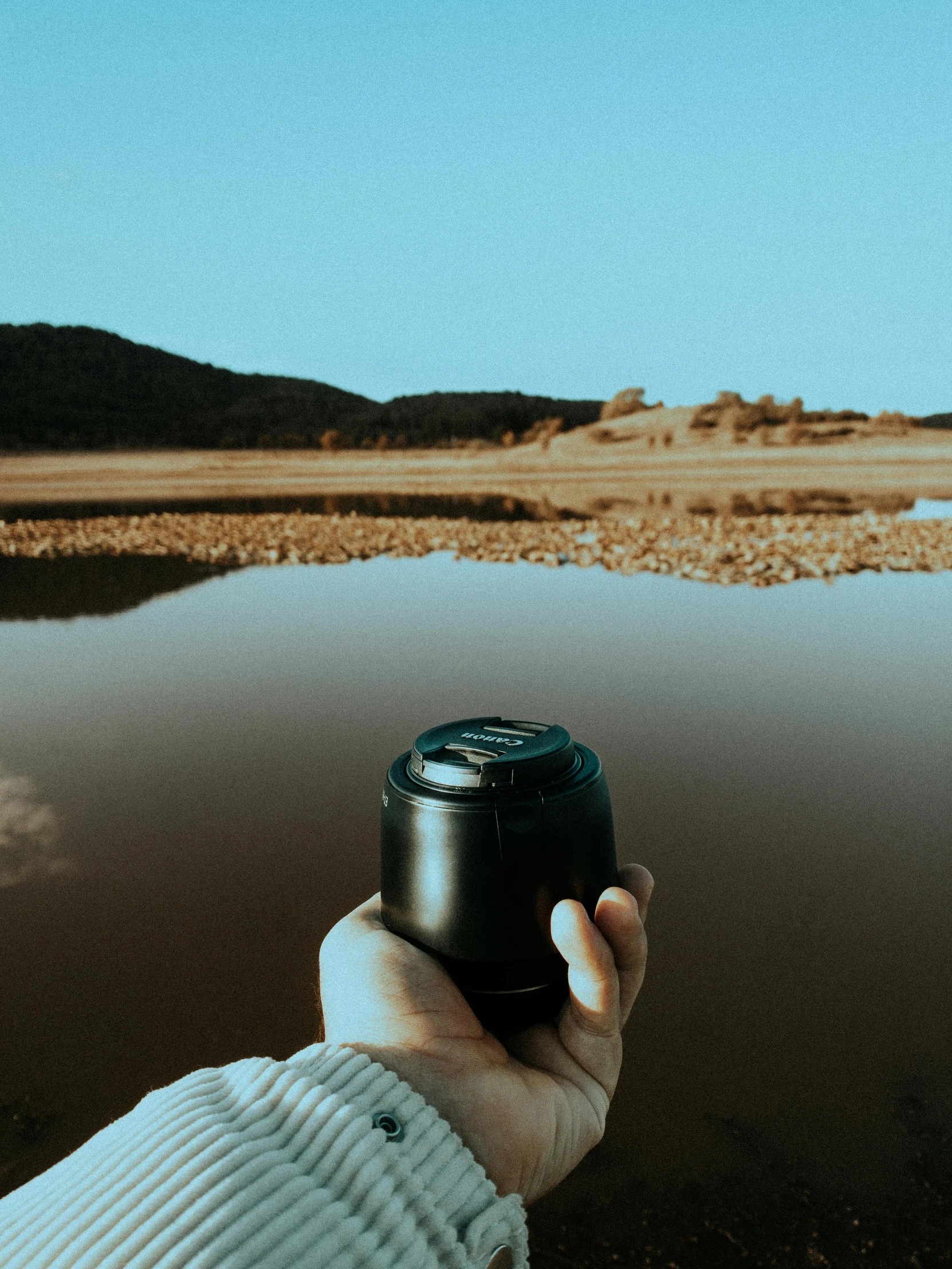 someone holding a camera taking a po of a lake