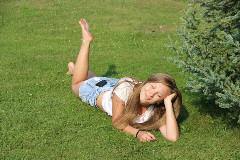 a girl in a field laying down with her head on her hand