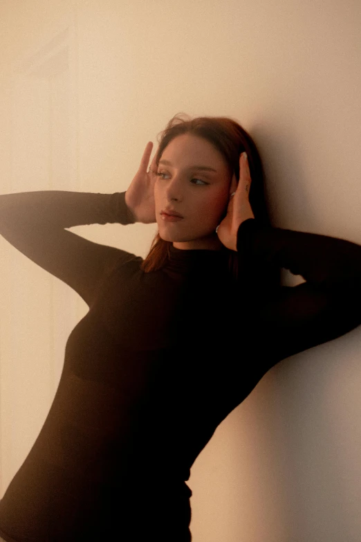 a woman wearing a black top leaning against the wall