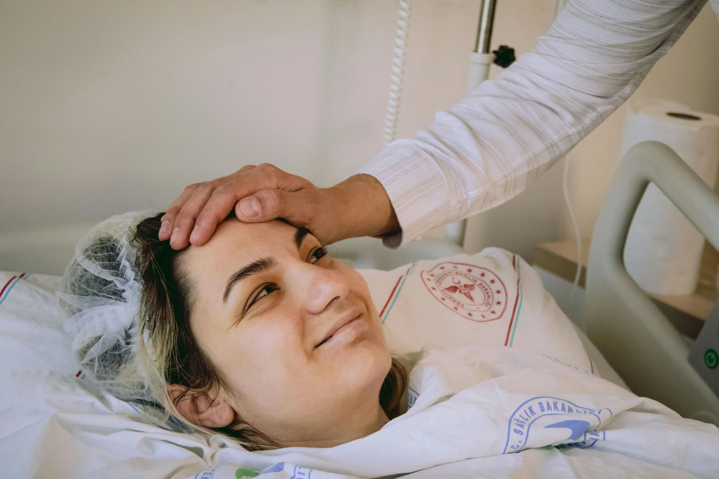 a woman in a hospital bed with a nurse helping her