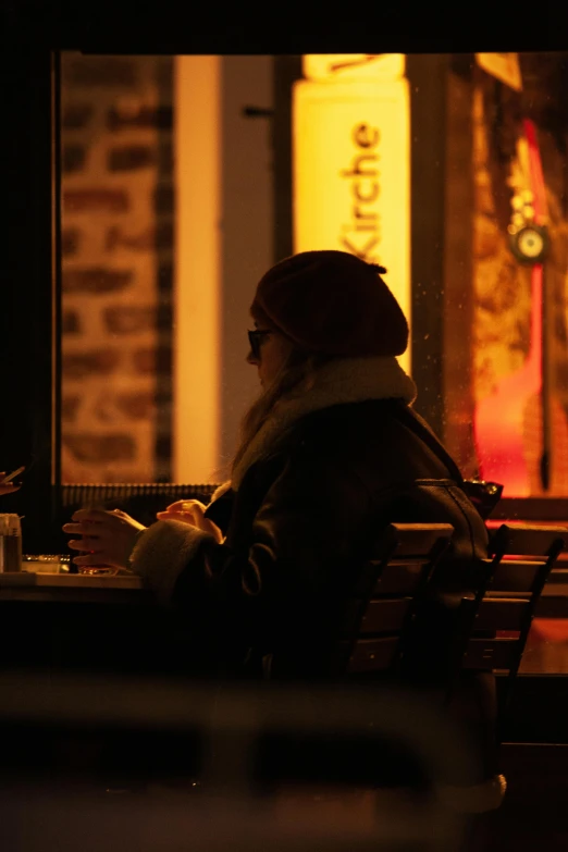 a woman sits on a bench reading in the middle of a dark room