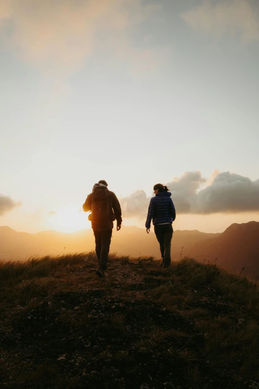 two people walking on the top of a mountain together