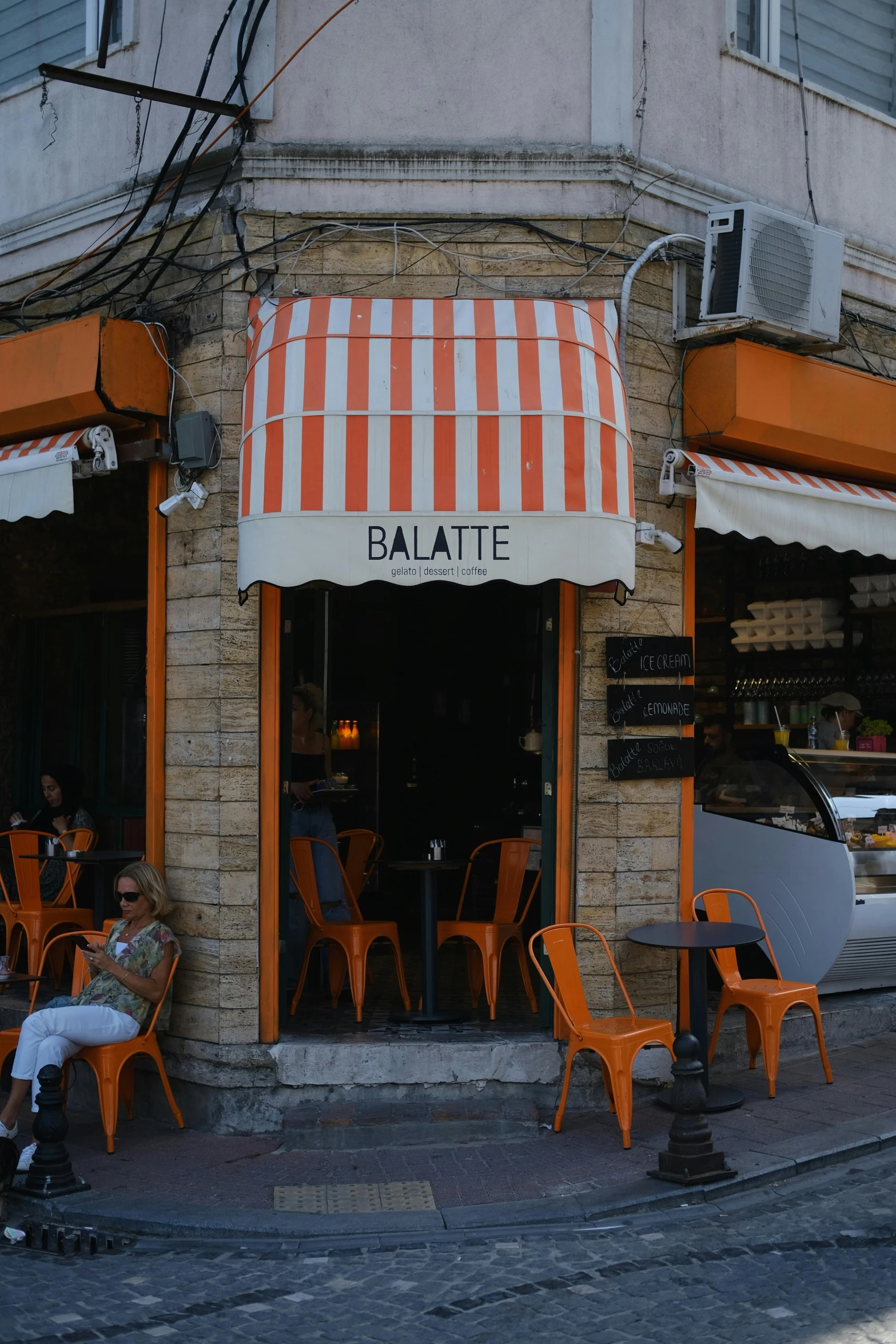 a cafe with many orange chairs on the side of the street