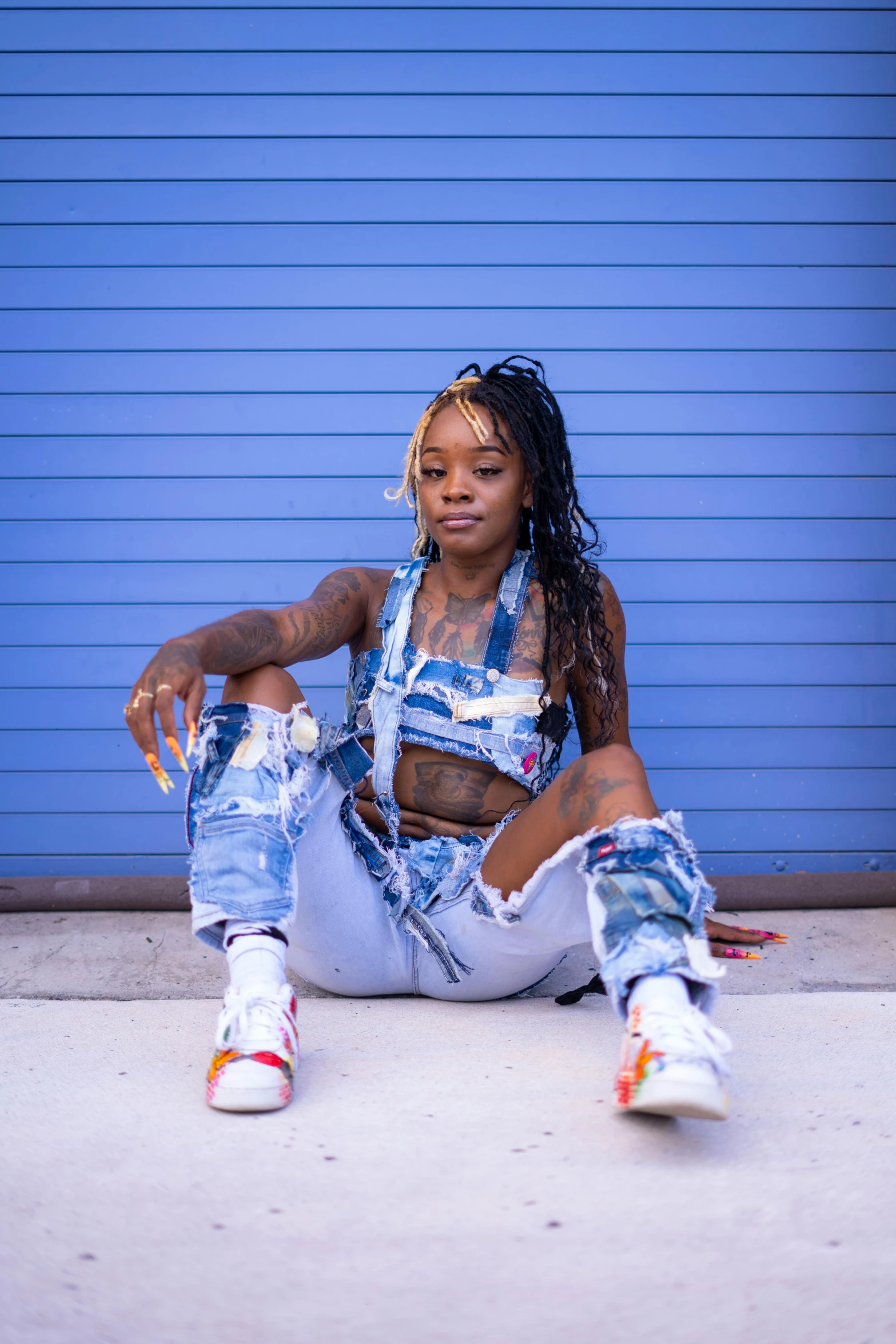 a young woman sits on the ground near blue doors