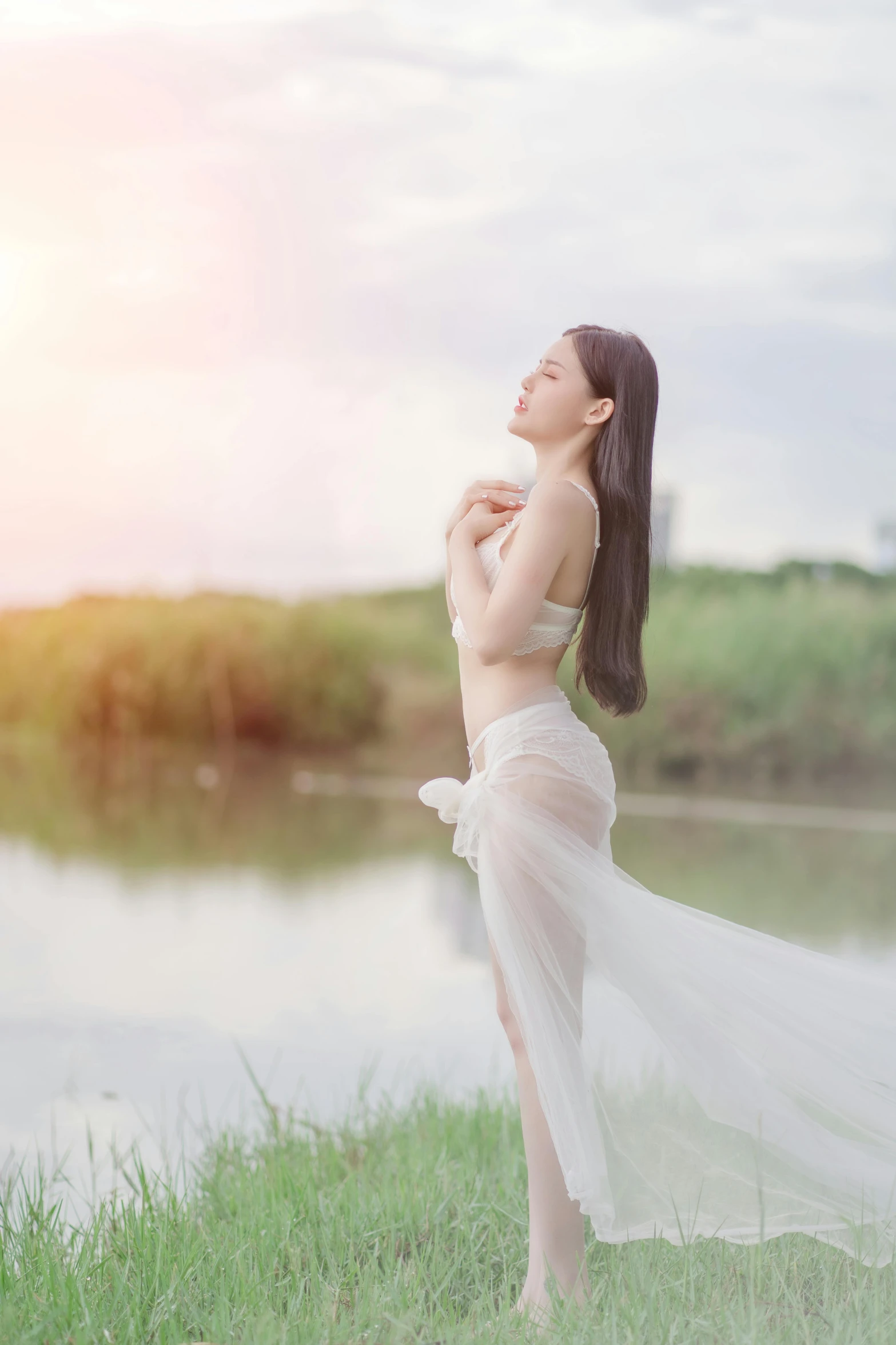 a woman standing in a field near a body of water