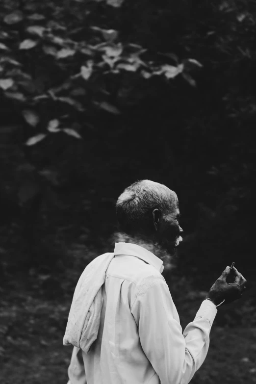 a man walking through a wooded area holding a cell phone