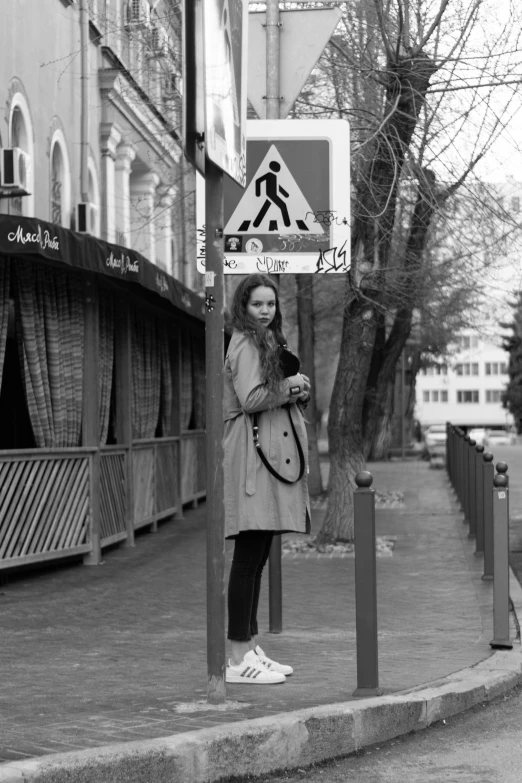 a woman standing by a road side with her hands clasped