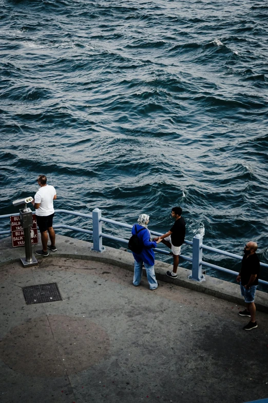 people are standing on a ledge and walking towards the water