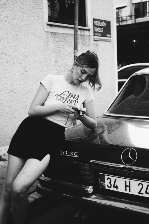 black and white po of a woman leaning on an old car