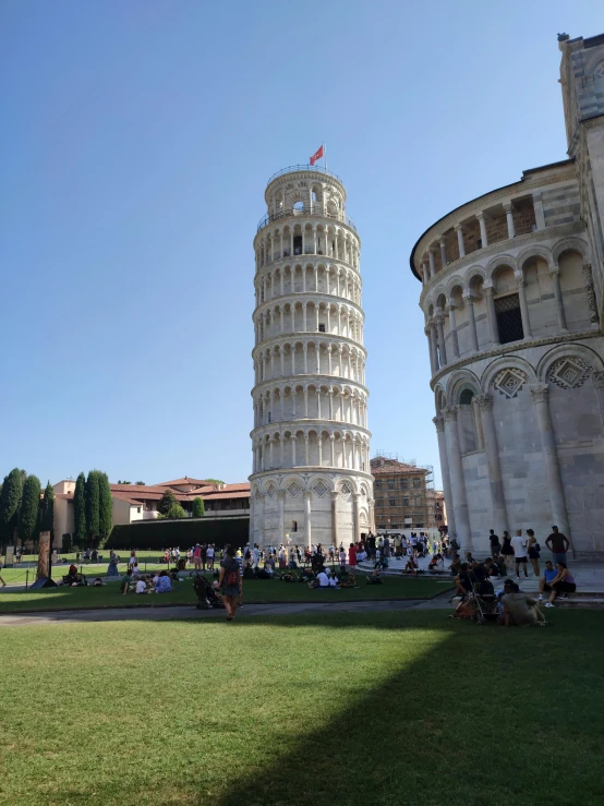 people walk in front of the leaning tower in pisa
