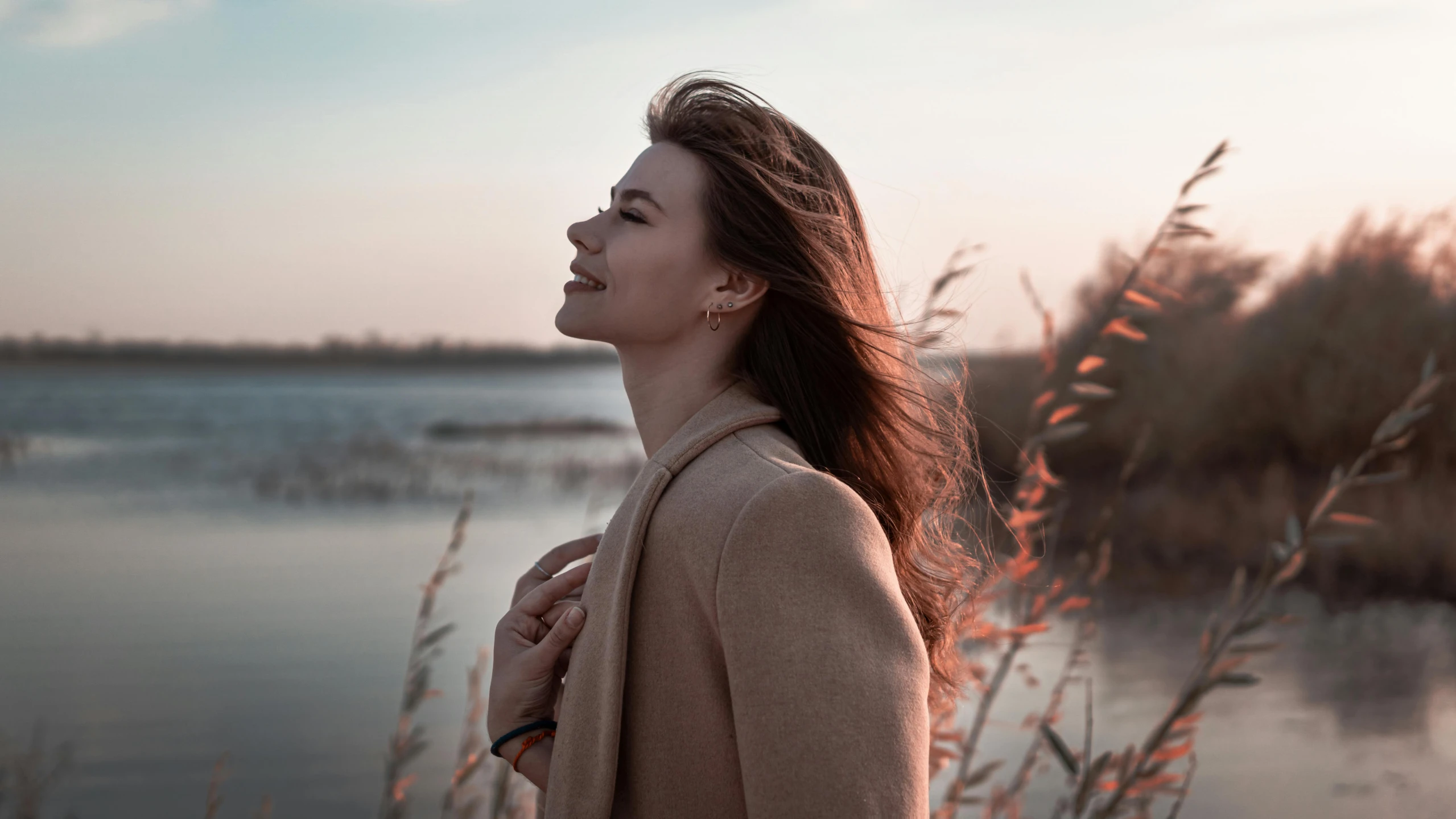 a woman stands close to water in a field