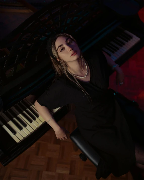 a woman wearing black is leaning on an upright piano