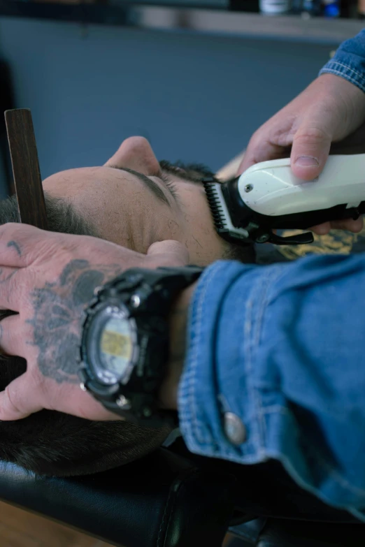 the young man is triming his face with the hair clippers