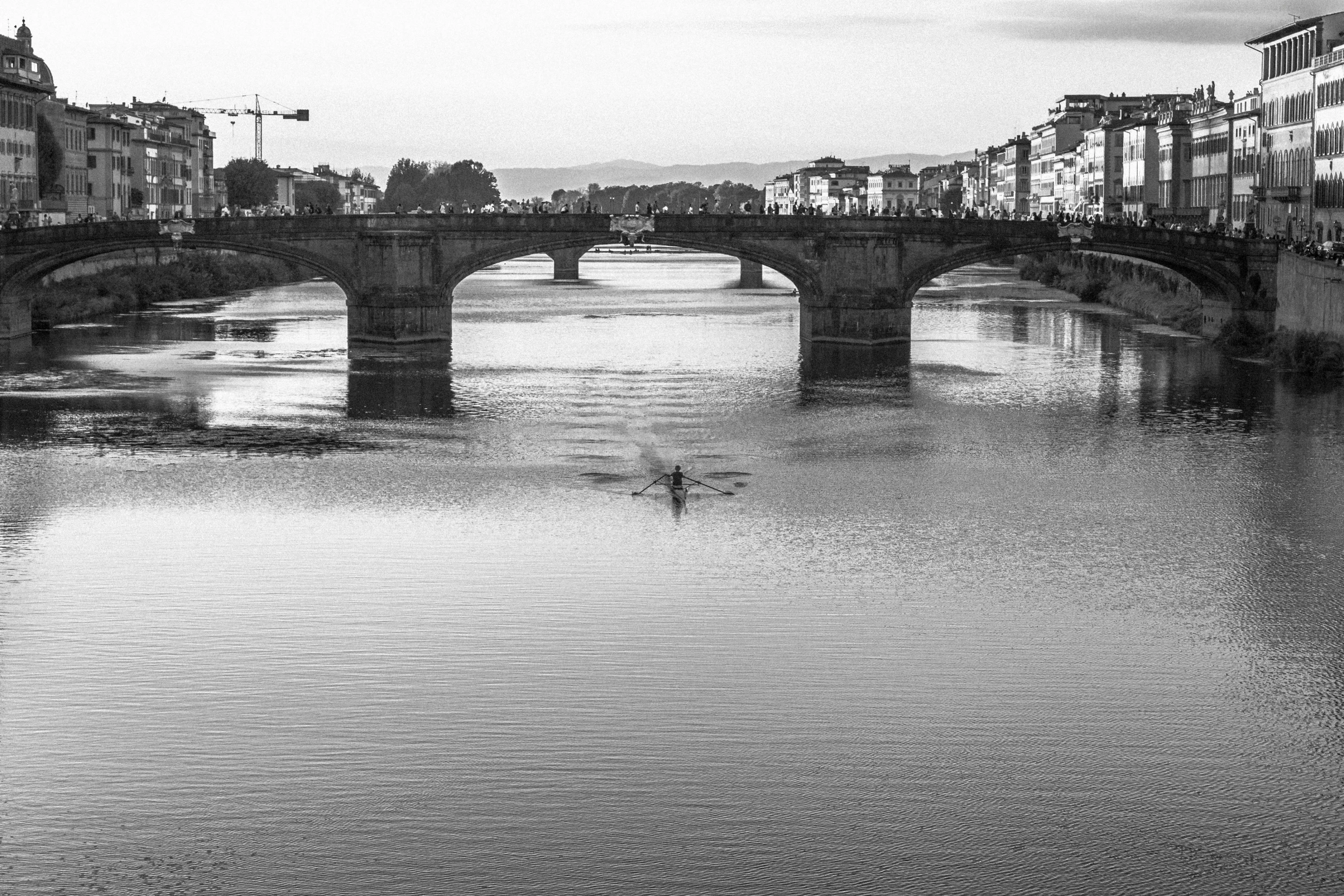 a man swimming in the river under an old bridge