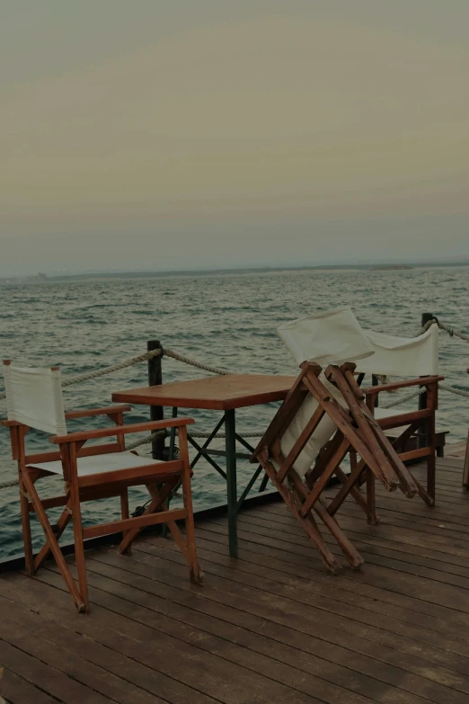 wooden deck chairs and a table on a pier