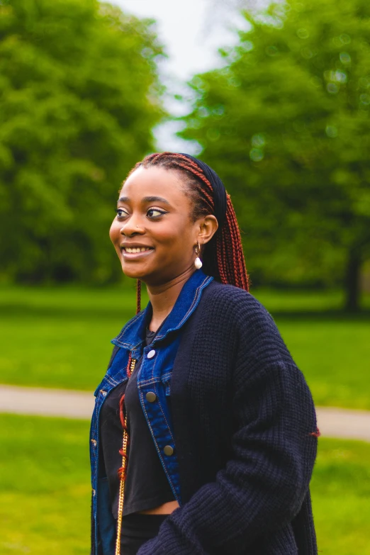 a woman smiling with her head up near green trees