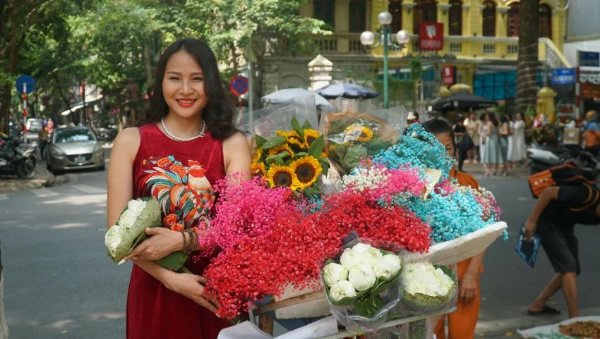 a woman stands on the sidewalk holding flowers and holding a basket