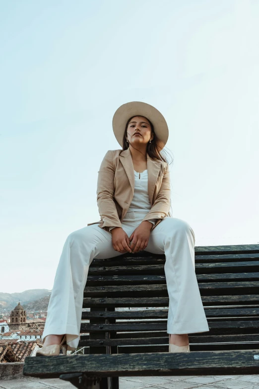 a woman with a hat and suit sitting on a bench