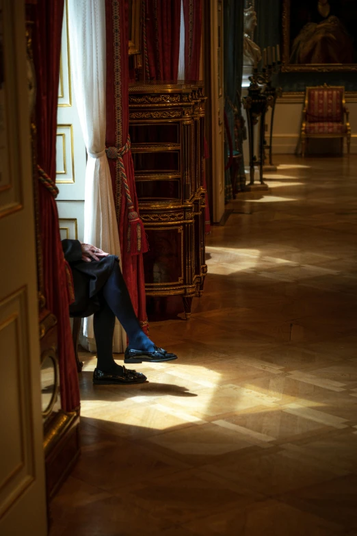 man in blue sitting alone near large dresser