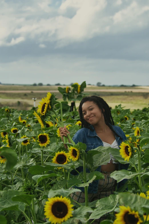 a young woman sitting on top of a sunflower field