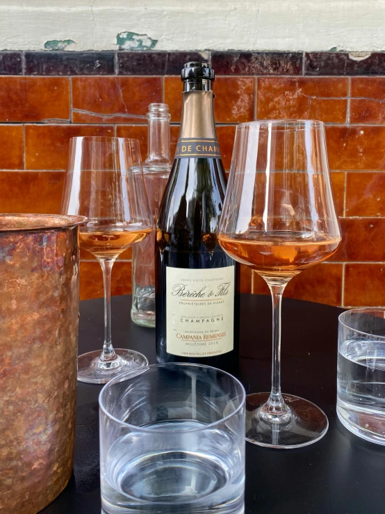 some wine glasses are on a table with bottles and drinks