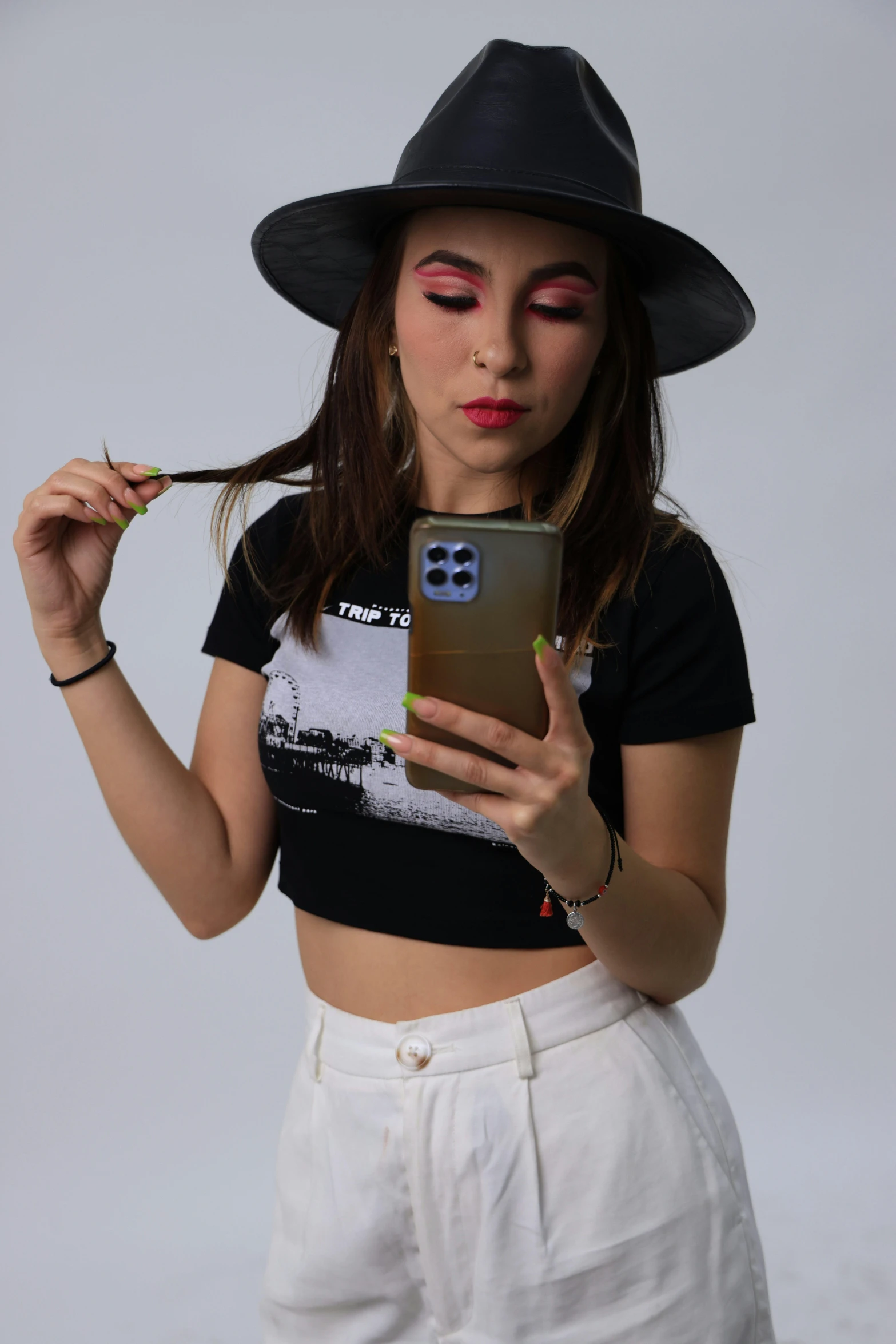 a young woman in black hat and shirt looking at a phone