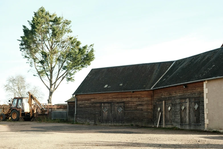 a tractor is parked outside of an old barn