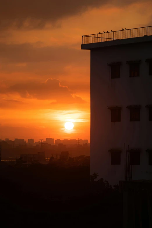 the sun is setting behind a tall building