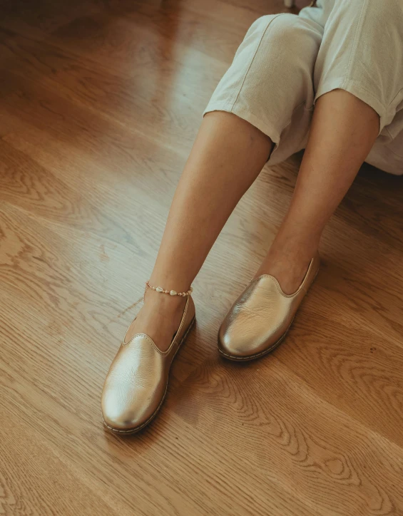 close - up of woman's legs in shiny gold flat shoes