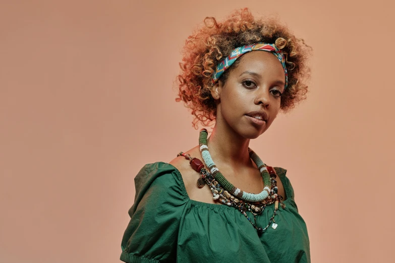 woman with afro and statement necklaces wearing a green blouse