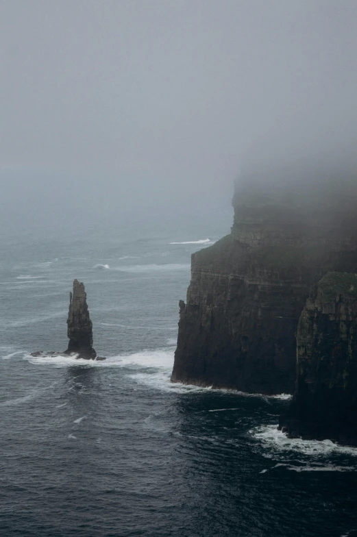 a small boat floating near a rocky cliff