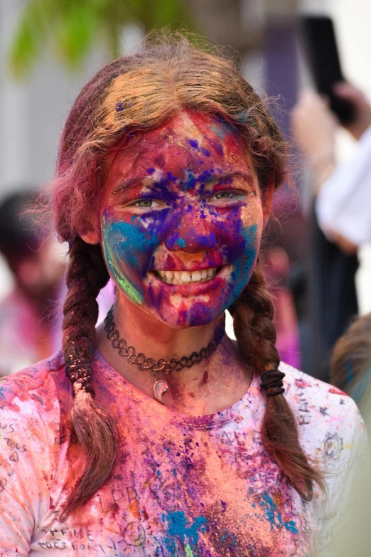 a girl with colored makeup and ids smiles for the camera