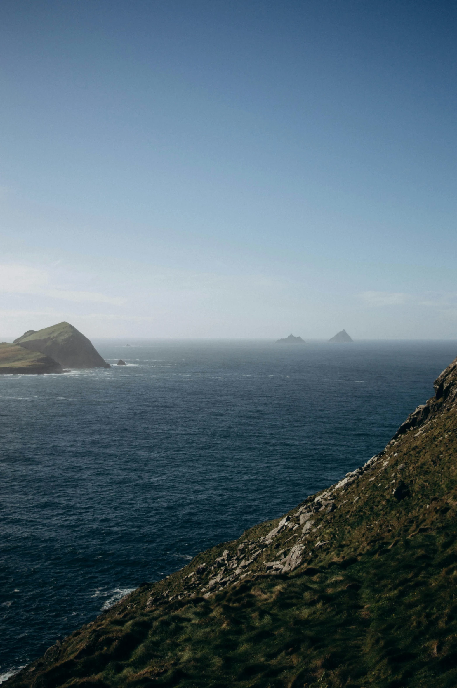 a man standing on top of a lush green hillside near the ocean