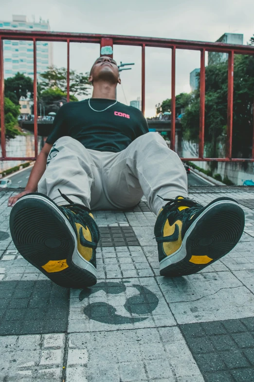 a person lying on the ground wearing black and yellow sneakers