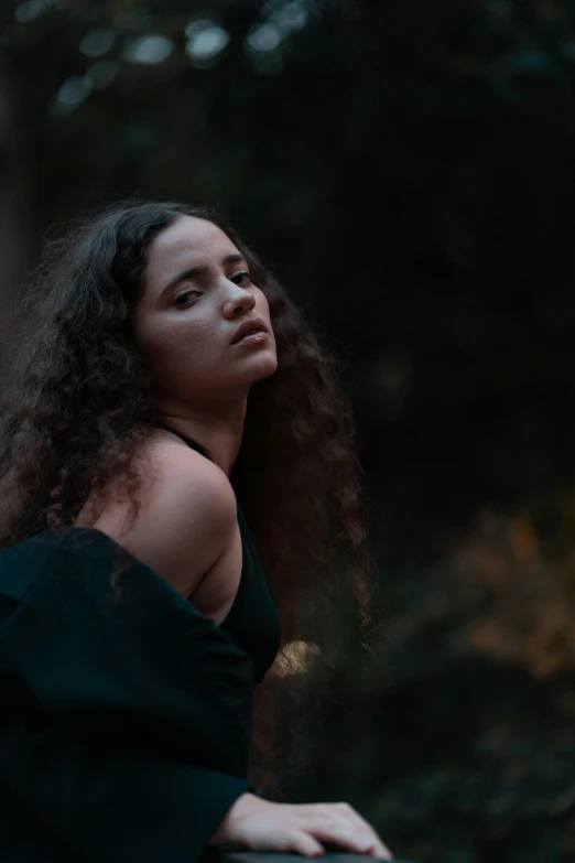 woman with curly hair in dark dress and looking back