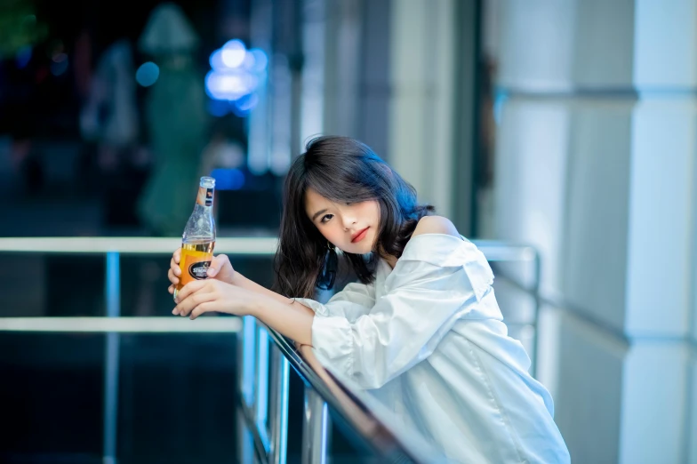 a young woman sitting at a balcony holding a beer
