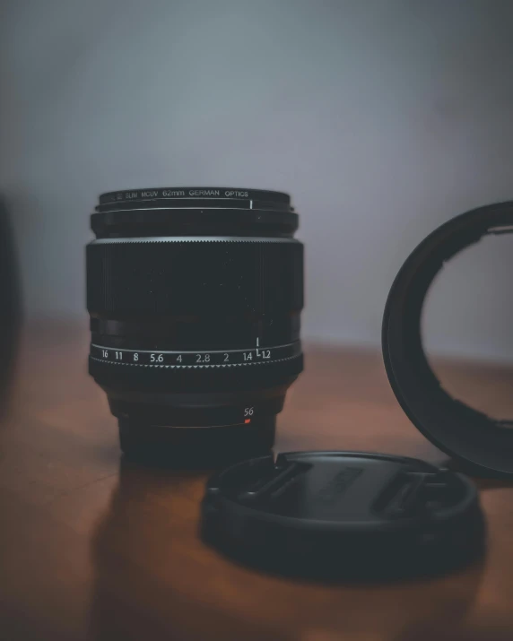 a black camera lens sitting next to a coffee cup on a table