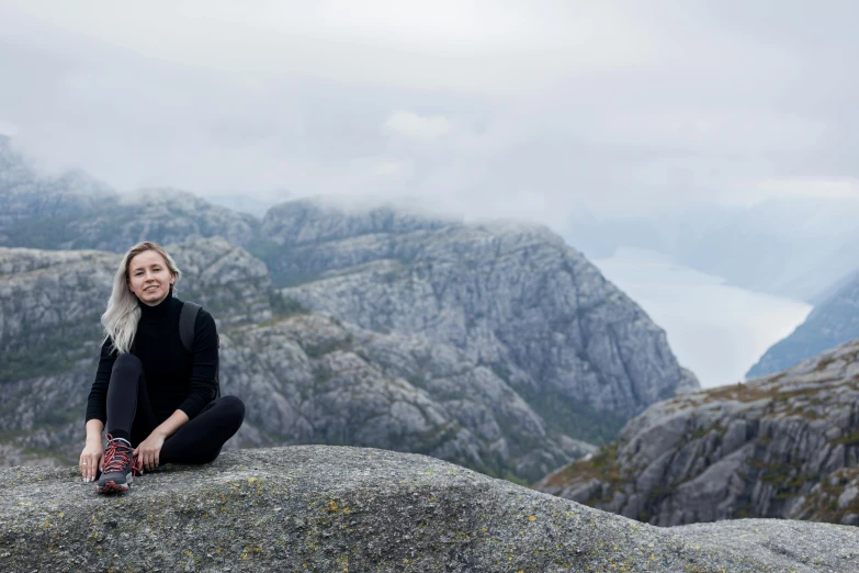 the blonde woman is sitting on top of a large rock