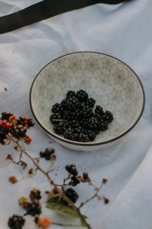 a bowl of berries and flowers on top of a table