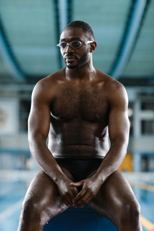 a black man wearing glasses sits on an inflatable ball