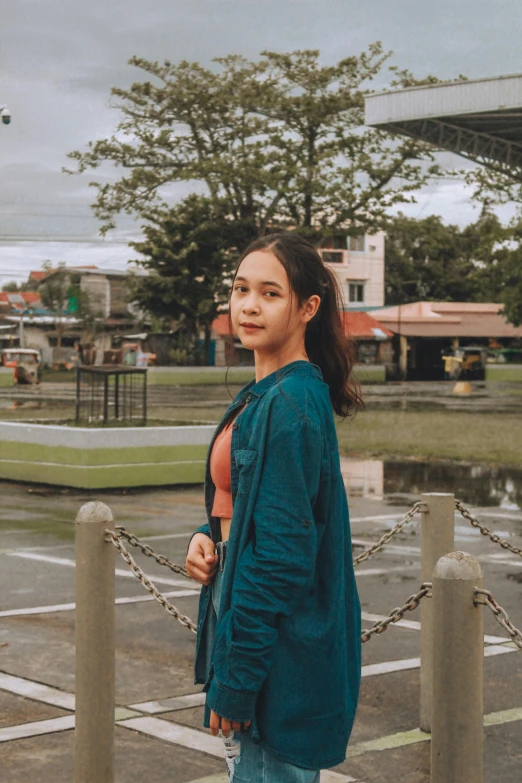 a woman standing in front of a fence on top of a rainy day