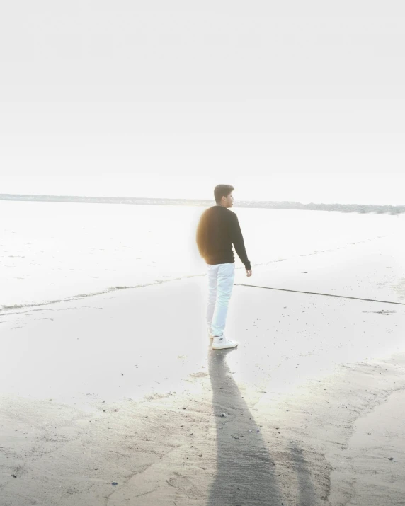 a person walking on the beach with their shadow cast