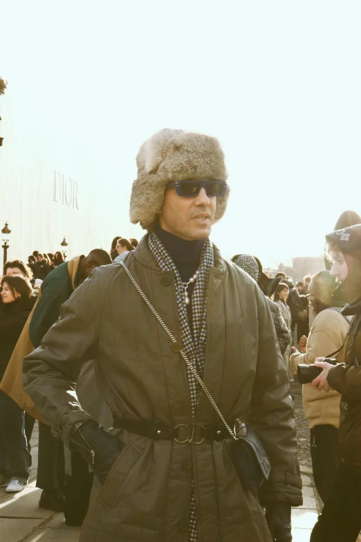 a man wearing a coat, hat and sunglasses