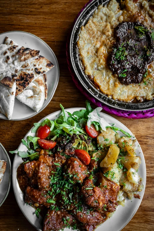 several plates on a wooden table with meat and vegetables